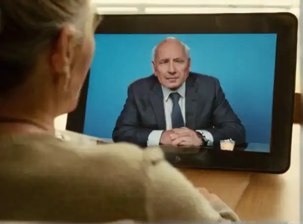 Senior person sitting in front of a computer screen with a tablet