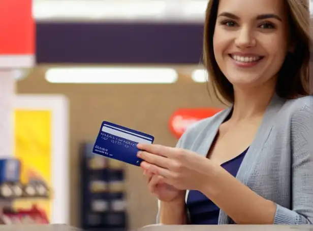 A person holding a credit card and smiling while shopping