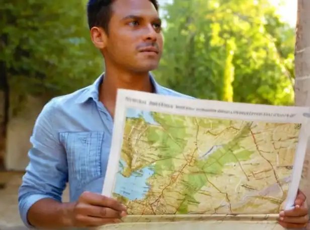 A person holding a map with a hopeful look and bright sunny background