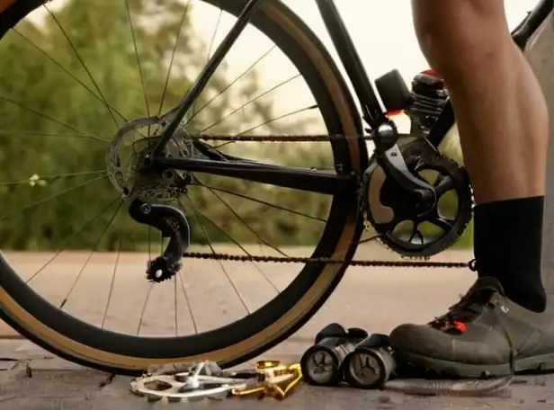 A cyclist leaning over a bike with gears and tools