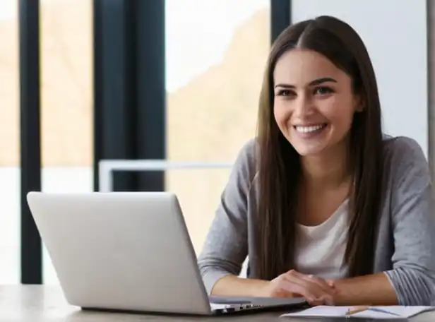 Woman sitting in front of laptop with smiling expression