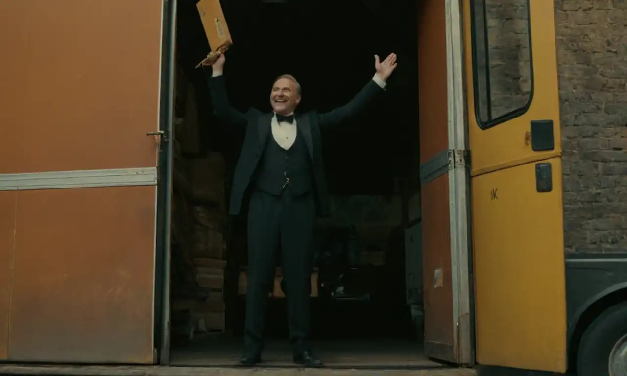 Un conductor sonriente apoyando el pie en la puerta de un garaje vacío