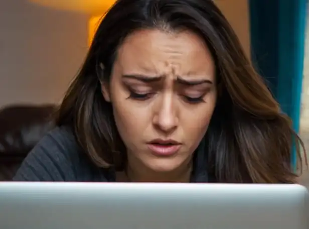 A person in front of a laptop with a worried expression