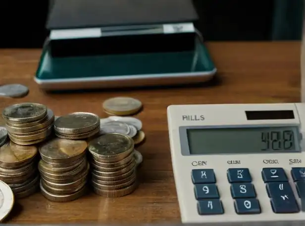 A calculator on a desk with coins and bills