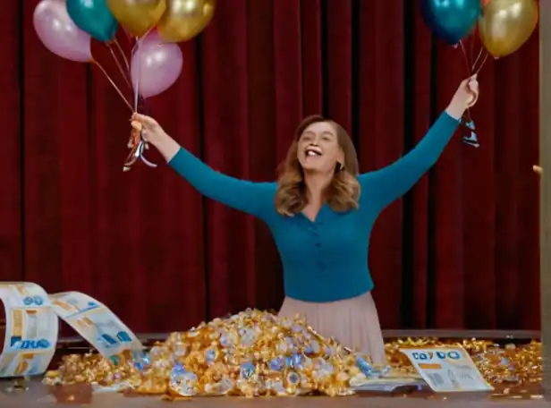 A winner holds a winning lottery ticket with confetti and balloons