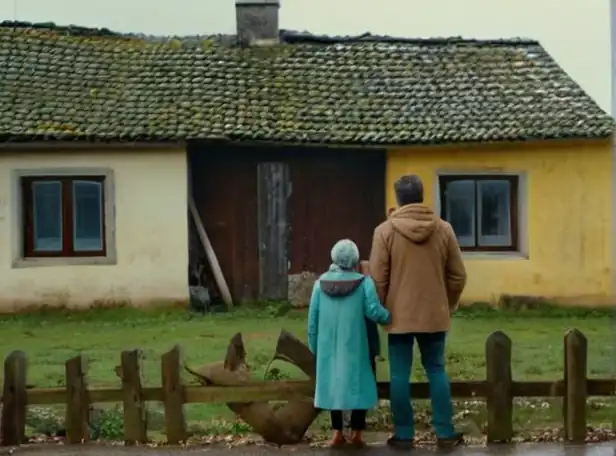 A struggling family standing in front of a worn-out house in a gloomy European city