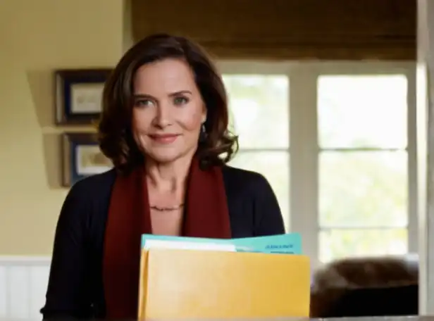 A woman proudly holding a retirement plan folder amidst a tidy home