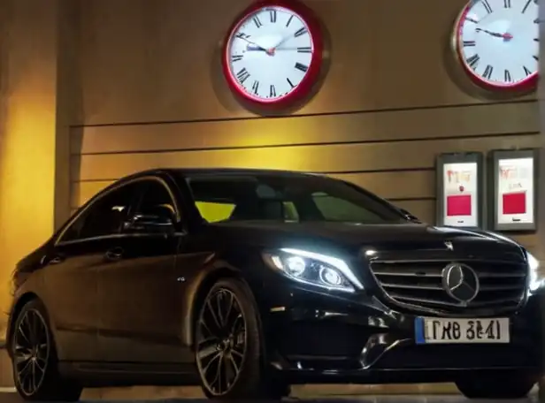 Driver waiting patiently in front of a clock with a car license