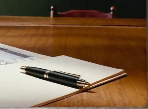 A clock surrounded by papers and pens on a desk