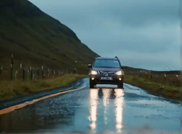 Rainy road with car driving carefully through puddles