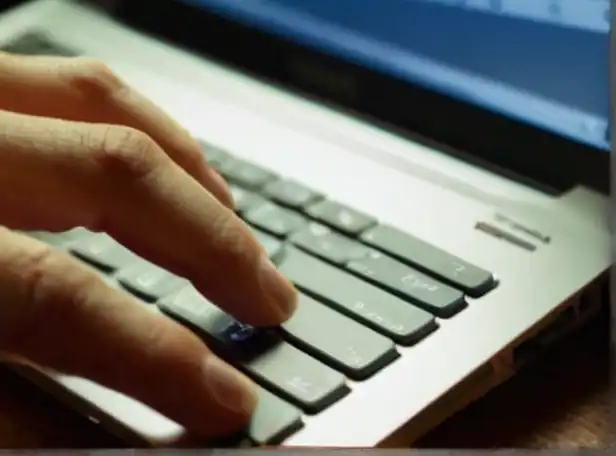 Hands typing on a laptop keyboard with soft glowing light