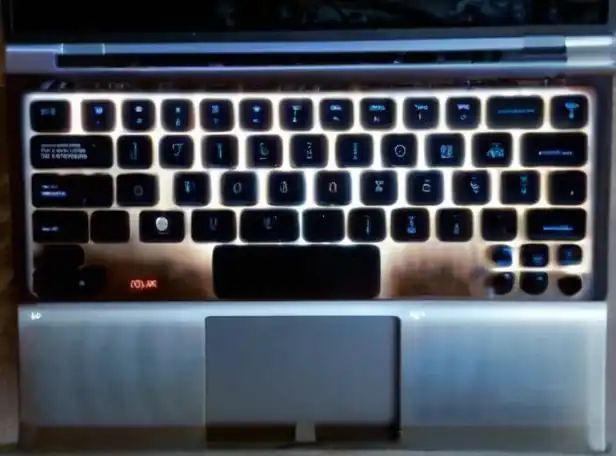 Keyboard backlight lit up on a laptop desk at night