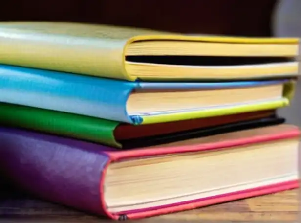 5 colorful book pages in a stack with a laptop background