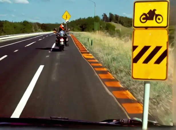 Motorcycles on highway shoulder with traffic signs and road markings