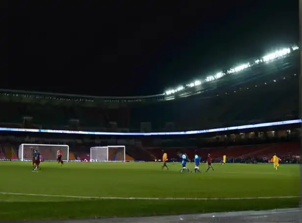 Football players on pitch under stadium lights at night