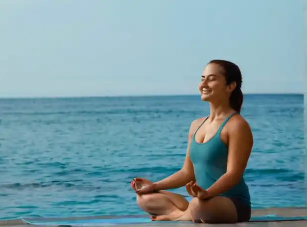 A person meditating by a calm ocean with a smile