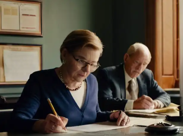 Retirees sitting at a desk amidst paperwork and pens