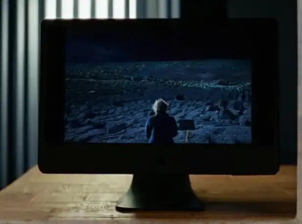 Mac computer screen in darkness with puzzled person nearby