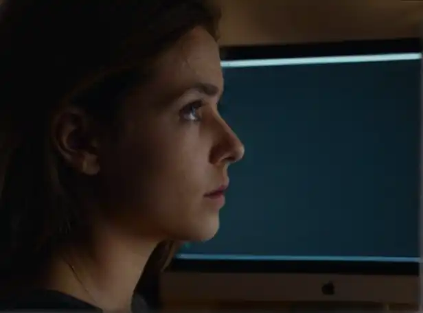 A dark Mac screen with a worried person looking at it