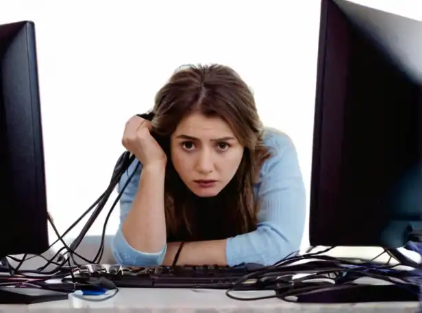 Frustrated person surrounded by frozen computer screens and tangled cords