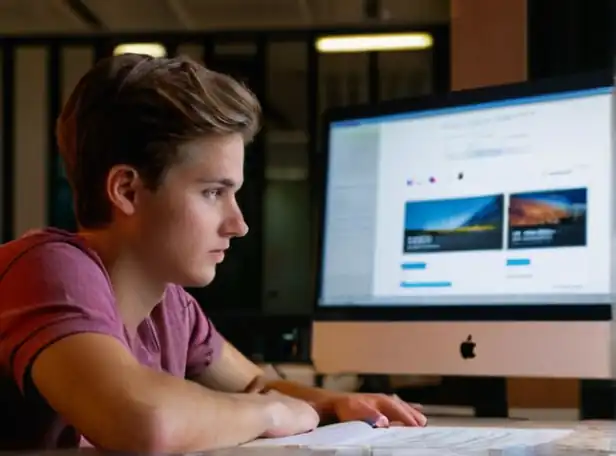 Young person sitting in front of computer screen with documents