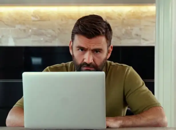 Man sitting at laptop with worried expression