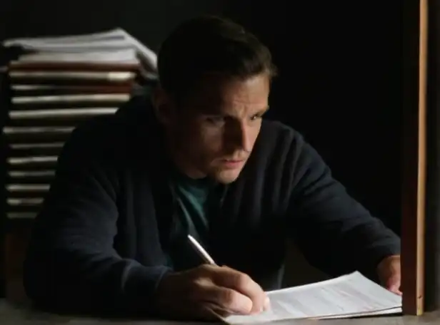 A concerned person looking at stolen documents in a darkened room