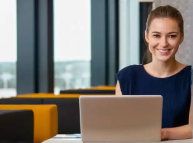 Young professional smiling in a modern office with laptop and notebook