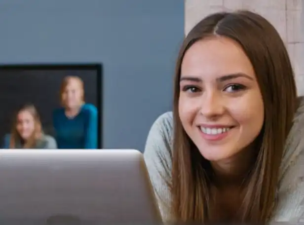 Young woman smiling in front of a laptop with euro notes