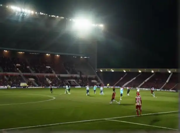 Football players battling on the pitch with stadium lights shining