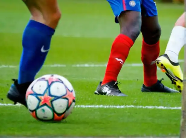 Soccer players battling on a green grass pitch