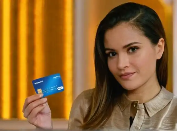 A woman frustratedly holding a frozen debit card with a computer in the background