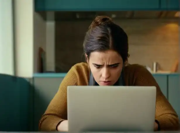 A person typing on a blocked online banking page with frustrated expression