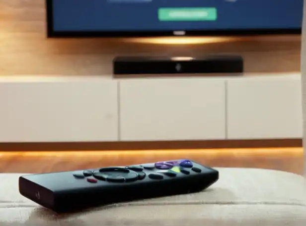 Smart TV remote control on a couch with a happy family