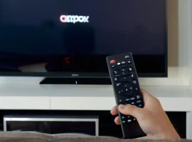 A person sitting on a couch in front of a Smart TV holding a remote control